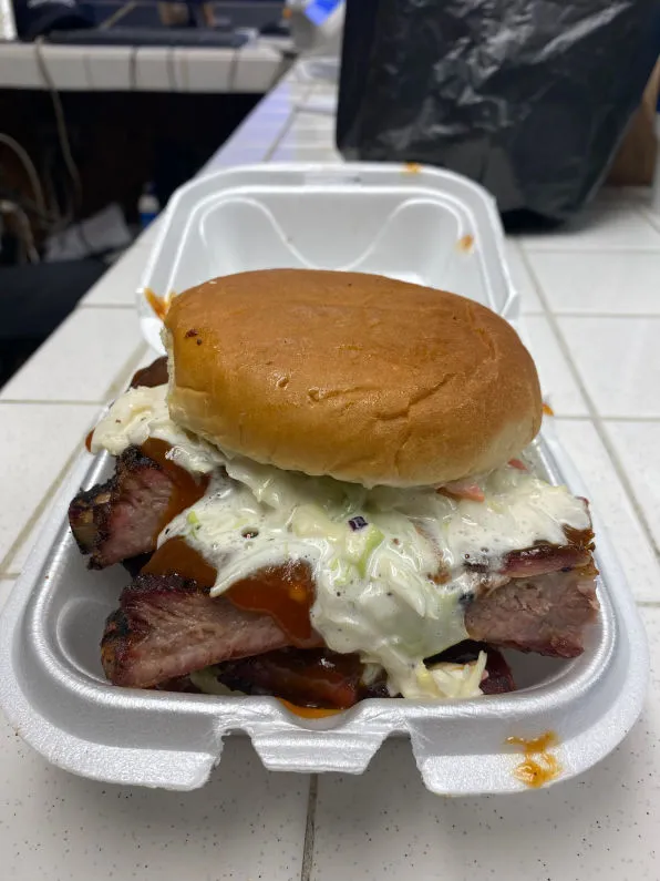 An overstuffed rib sandwich piled with smoked ribs and coleslaw on a fresh bun